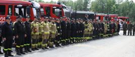Strażacy oraz WOT-owcy w szyku, w tle pojazdy pożarnicze