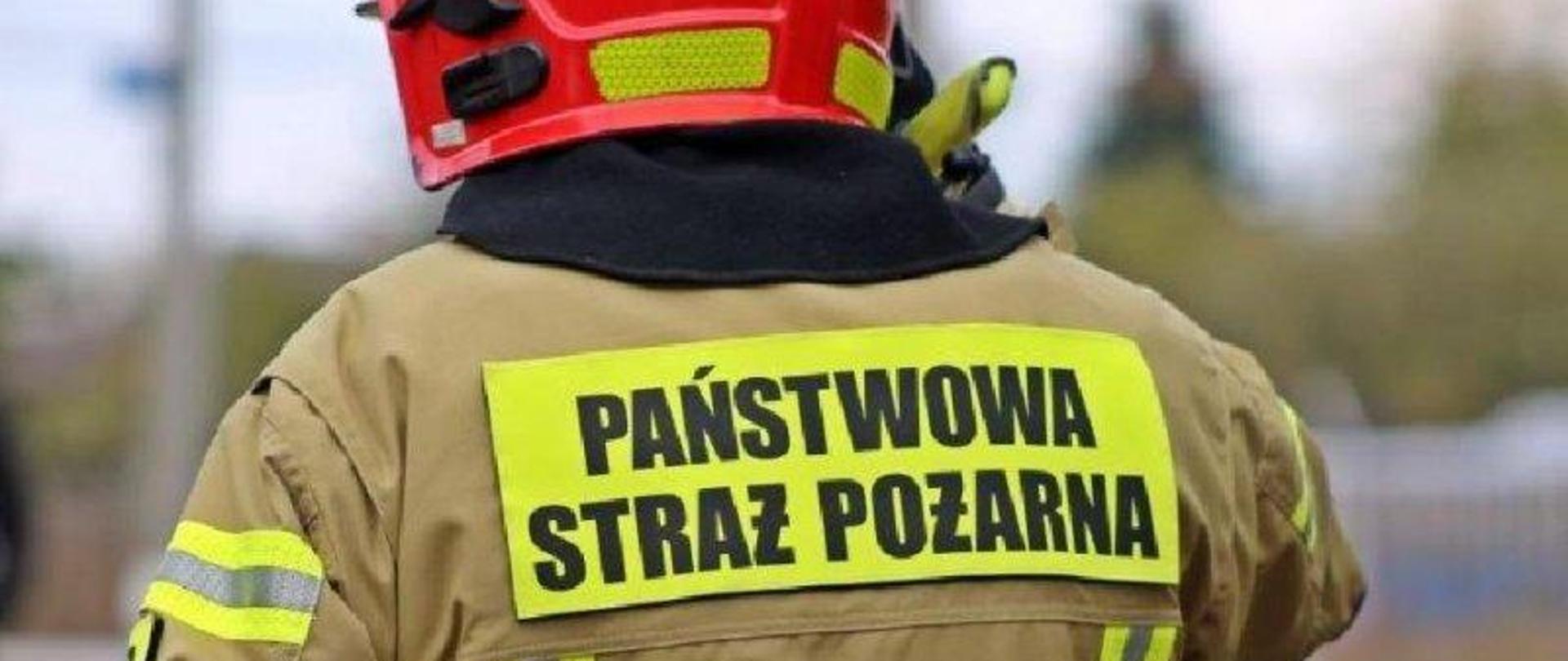 Strażak odwrócony plecami, napis Państwowa Straż Pożarna na plecach