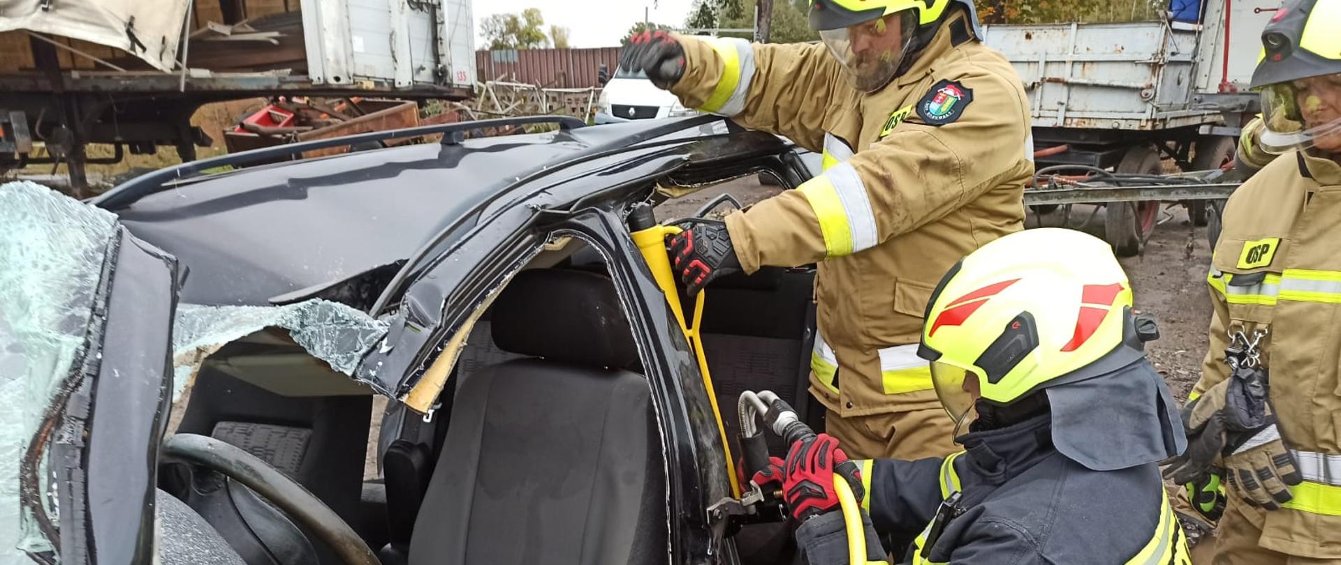 Zdjęcie przedstawia strażaka podczas rozpierania konstrukcji samochodu z użyciem narzędzi hydraulicznych.