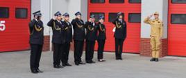 Widok z boku. Kadra Komendy Powiatowej PSP w Wadowicach salutuje podczas śpiewania hymnu Rzeczpospolitej Polskiej. 