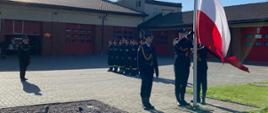 Podczas zmiany służbowej zebrani na placu Jednostki Ratowniczo-Gaśniczej w Rypinie funkcjonariusze Państwowej Straży Pożarnej, oczekują na podniesienie Flagi Państwowej na maszt. Flagę na maszt zaczepia poczet flagowy złożony z trzech funkcjonariuszy.