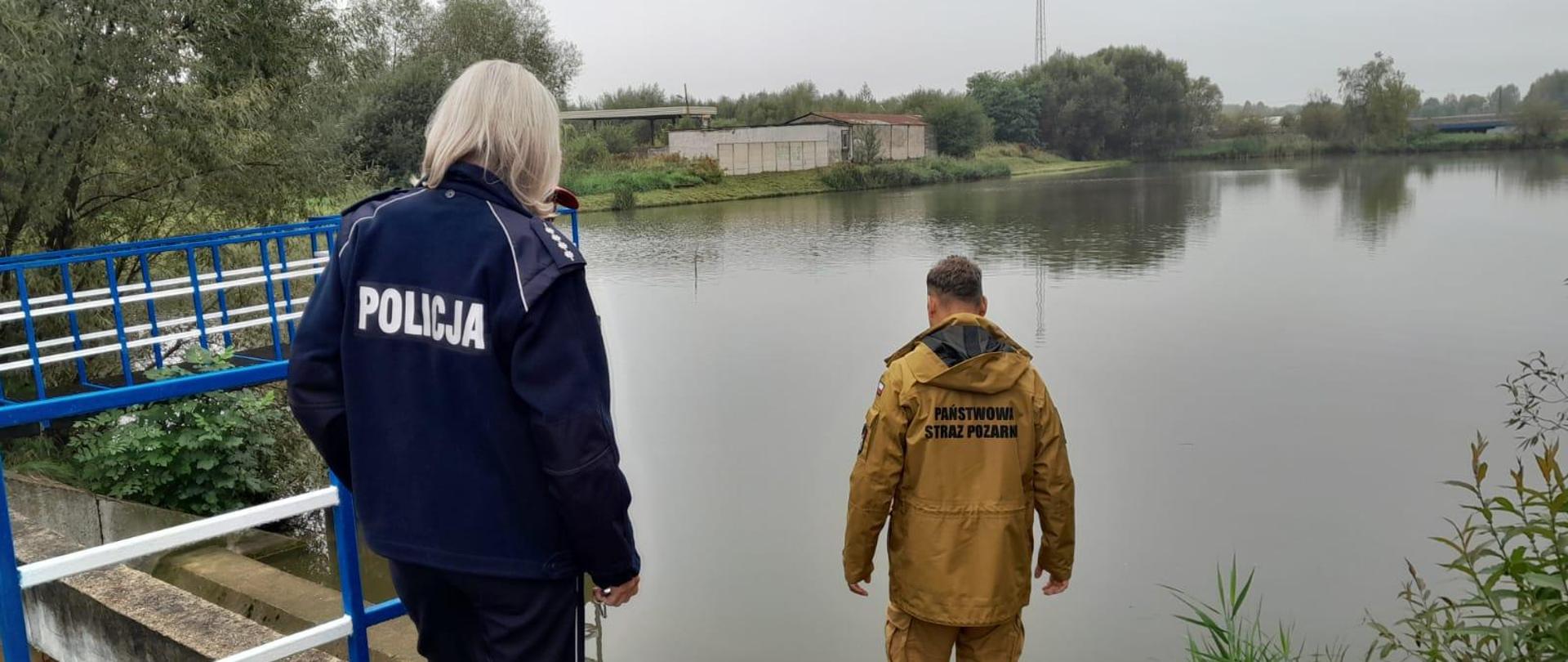 Zdjęcie przedstawia funkcjonariuszy kontrolujących zbiornik wodny