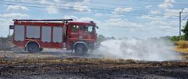 Samochód strażaki jeździ po ściernisku i dogasza palącą się słomę