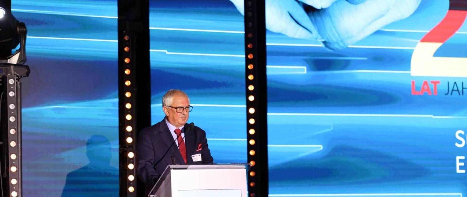 Deputy Minister Grzegorz Piechowiak stands in front of the lectern, speaking at the gala on the 25th anniversary of the Polish-German Chamber of Industry and Commerce 