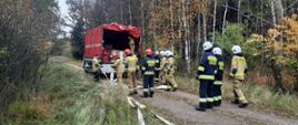 Na zdjęciu na leśnym dukcie ustawiony Samochód Specjalny Wężowy. Obok niego strażacy w umundurowaniu specjalnym, którzy rozwijają węże.