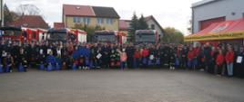 Zdjęcie zbiorowe członków OSP wraz z Młodzieżowymi Drużynami Pożarniczymi z terenu województwa zachodniopomorskiego na tle pojazdów pożarniczych