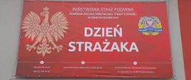 Baner "Dzień Strażaka" na ścianie budynku komendy przy placu zewnętrznym