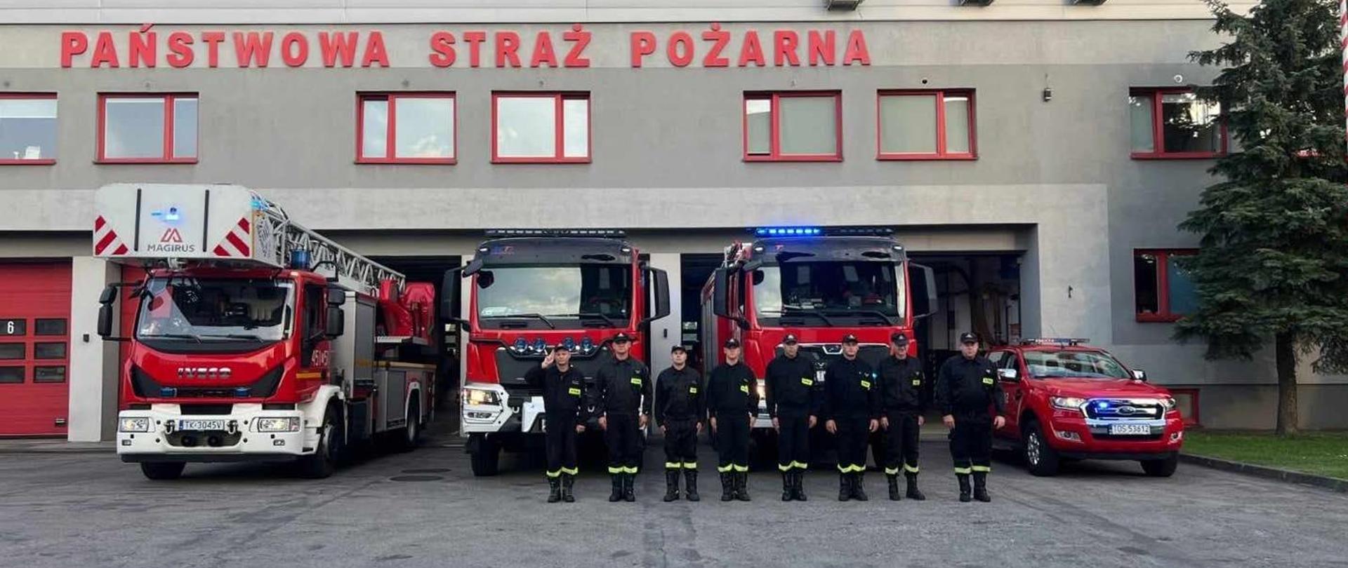 Na zdjęciu widoczni są strażacy na tle samochodów ratowniczo-gaśniczych oddający hołd tragicznie zmarłym strażakom z Komendy Miejskiej Państwowej Straży Pożarnej w Poznaniu.