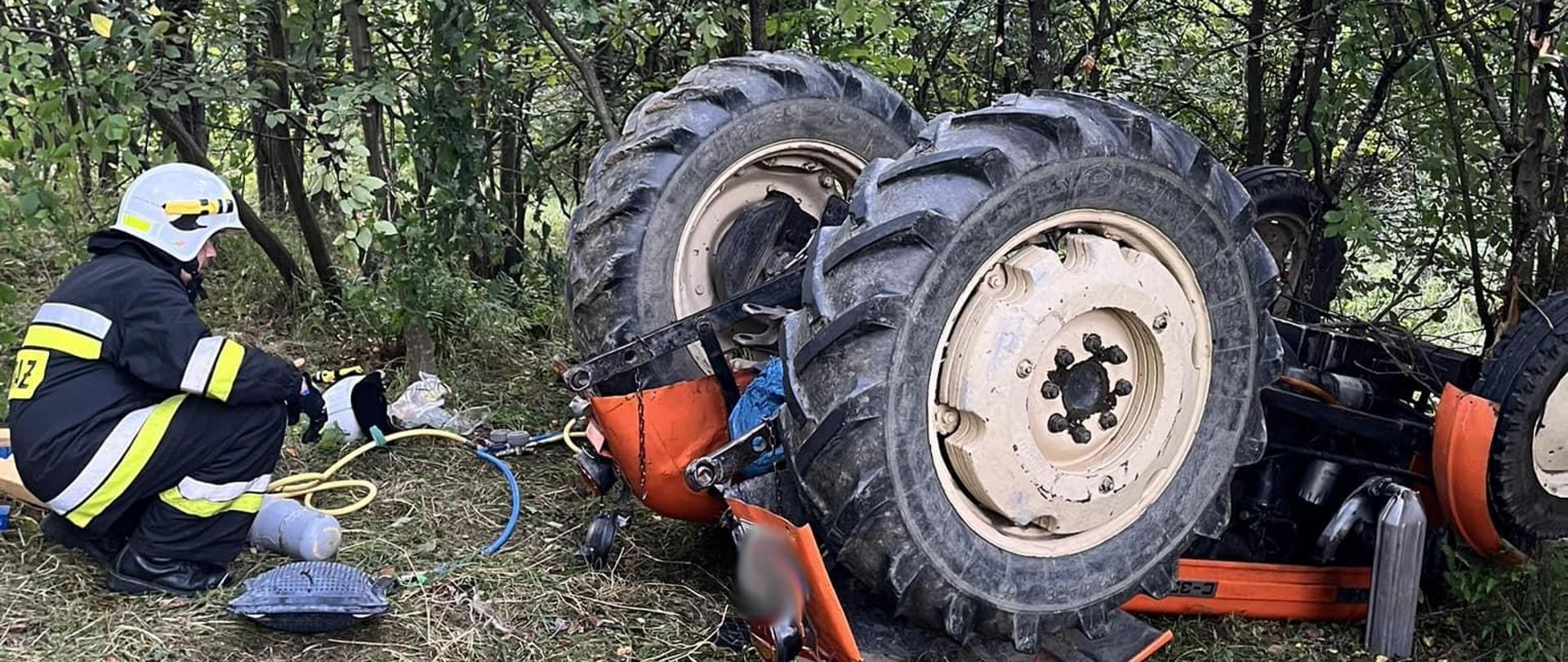 Ciągnik do góry kolami a obok strażak