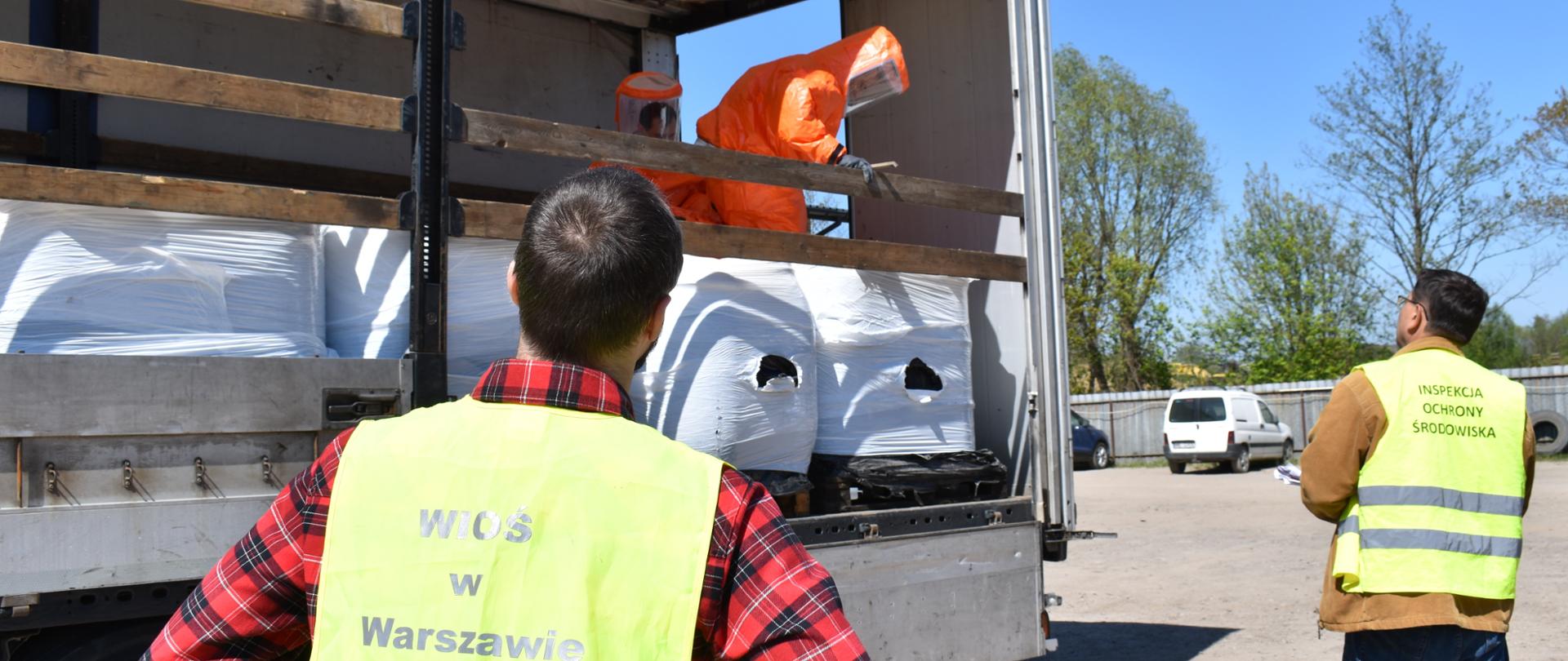Inspektorzy Wojewódzkiego Inspektoratu Ochrony Środowiska w Warszawie monitorują pobór próbek z beczek znajdujących się na naczepie samochodu ciężarowego.