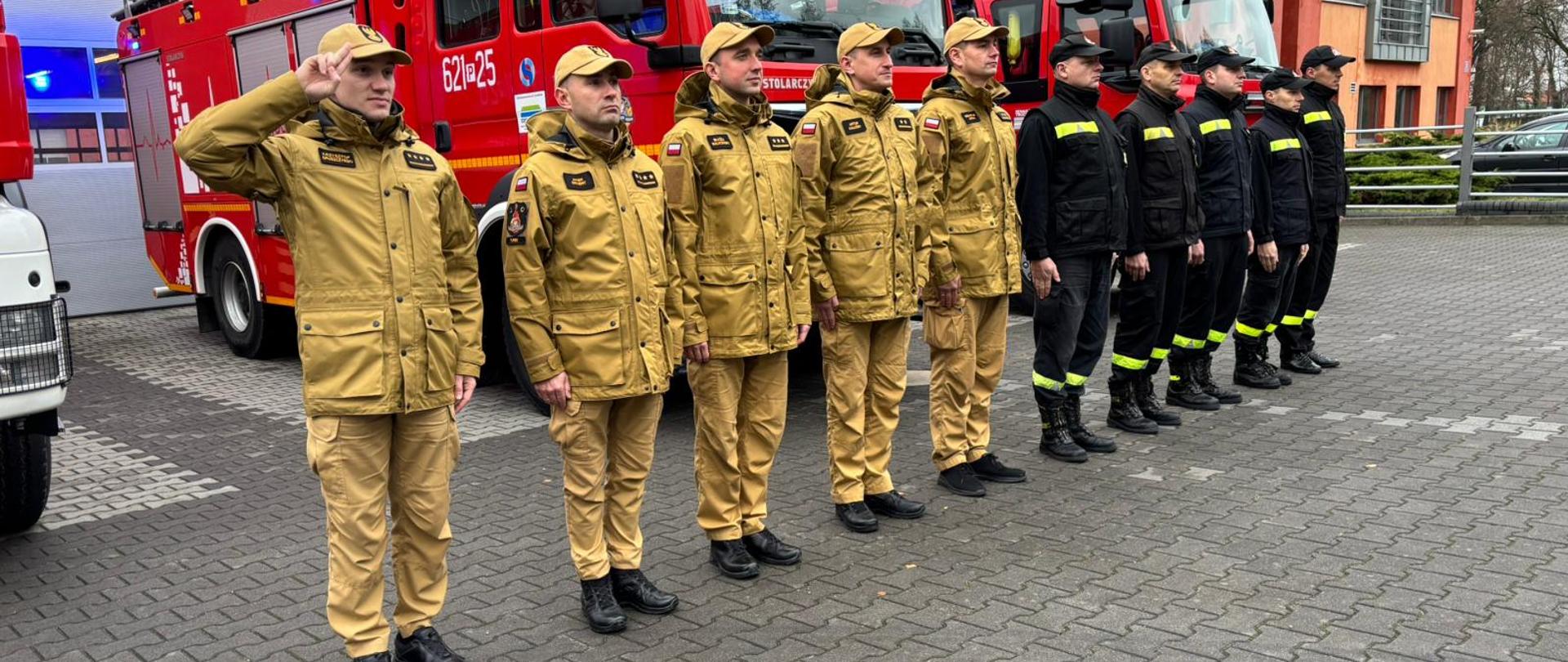 Strazacy na tle pojazdów pozarniczych w czasie oddawana hołdu.