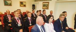 Na zdjęciu widzimy strazaków z medalami na szyjach oraz gości obecnych na spotkaniu.