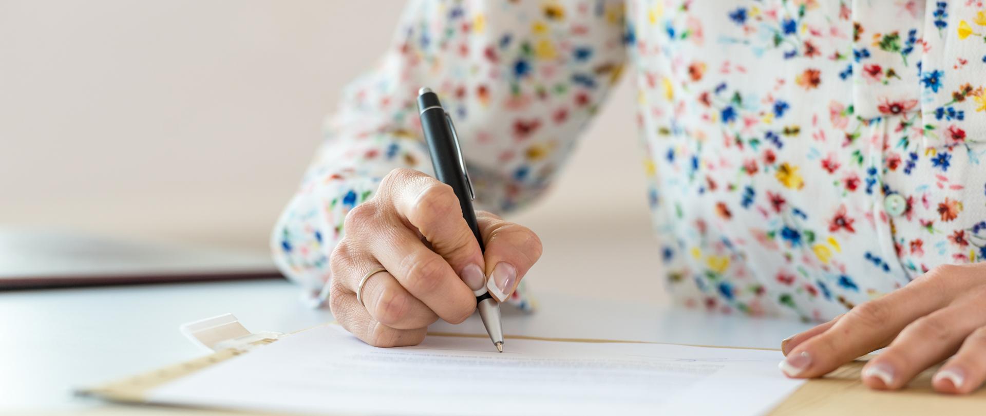 Businesswoman signing a document in a folder.