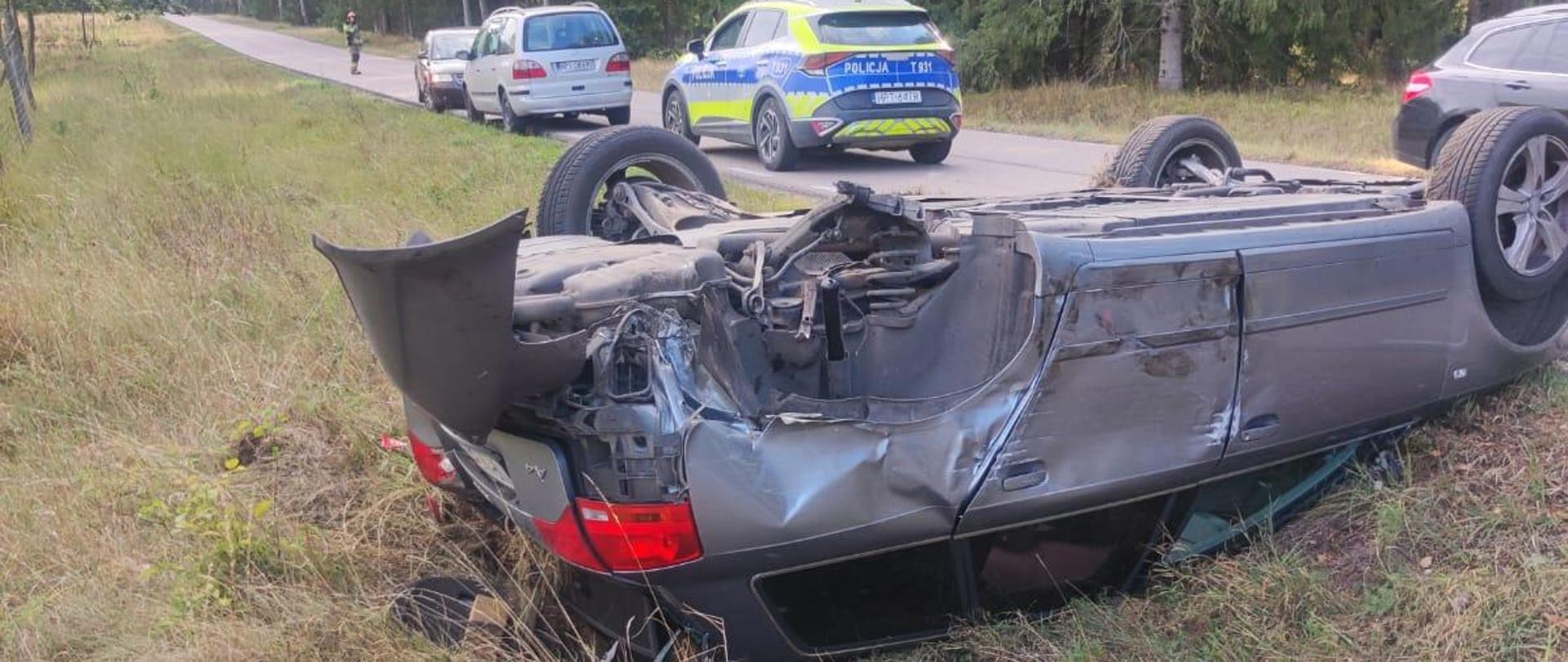 Samochód na dachu w rowie, w tle policja oraz samochody