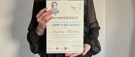 Uczennica trzymająca dyplom za zdobycie wyróżnienia w konkursie pianistycznym