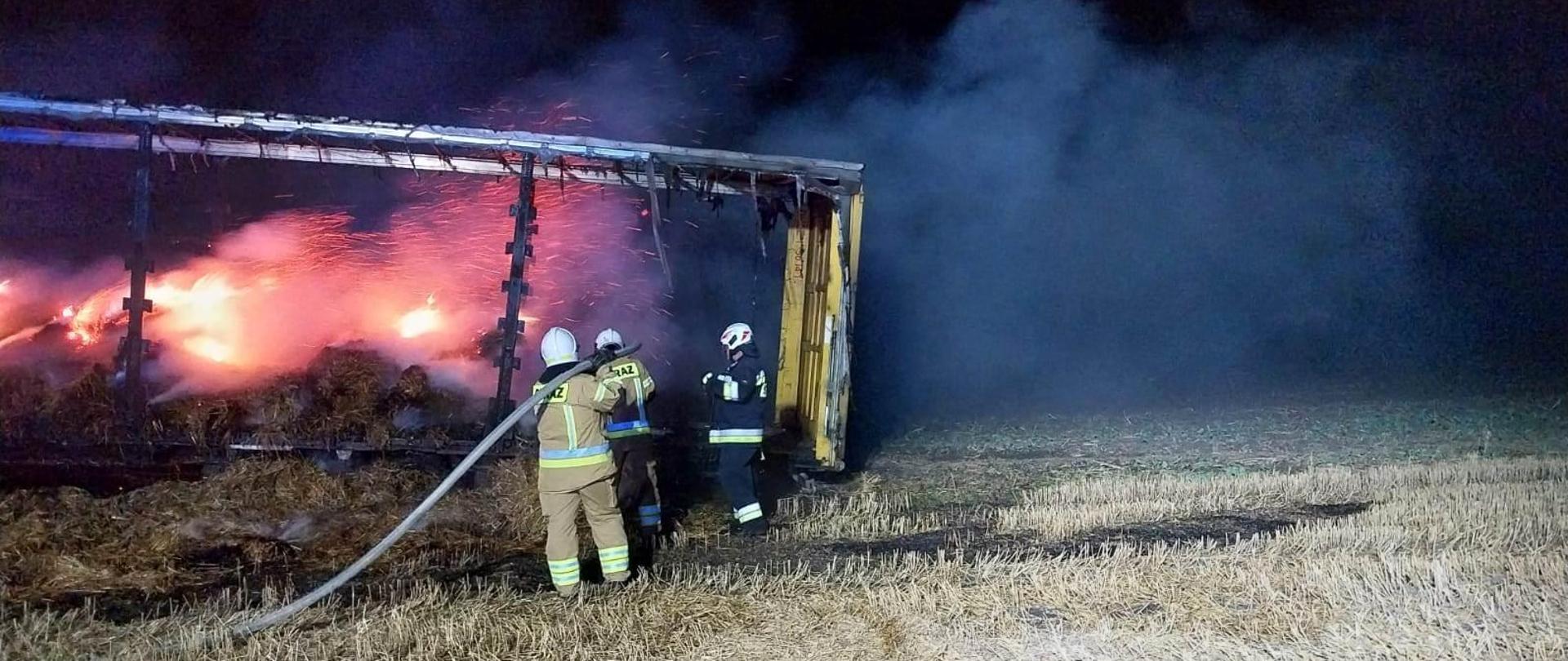 Pożar balotów na naczepie, strażacy gaszą, jest noc