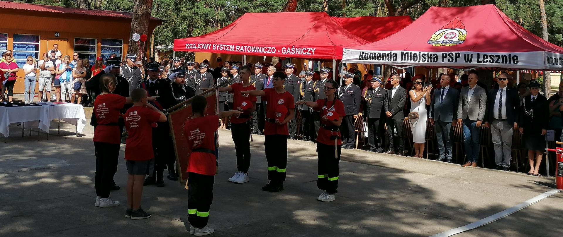 Zdjęcie przedstawia młodzież strażacką składającą ślubowanie podczas apelu na placu.