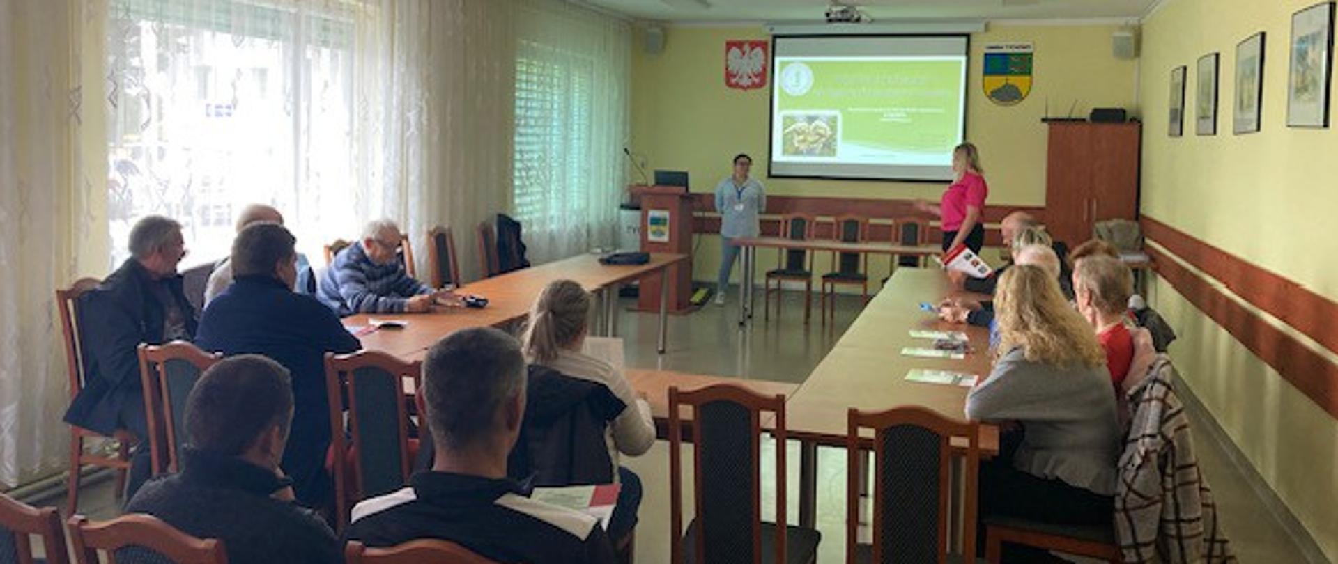 zdjęcie przedstawia ludzi siedzących na sali i biorących w szkoleniu