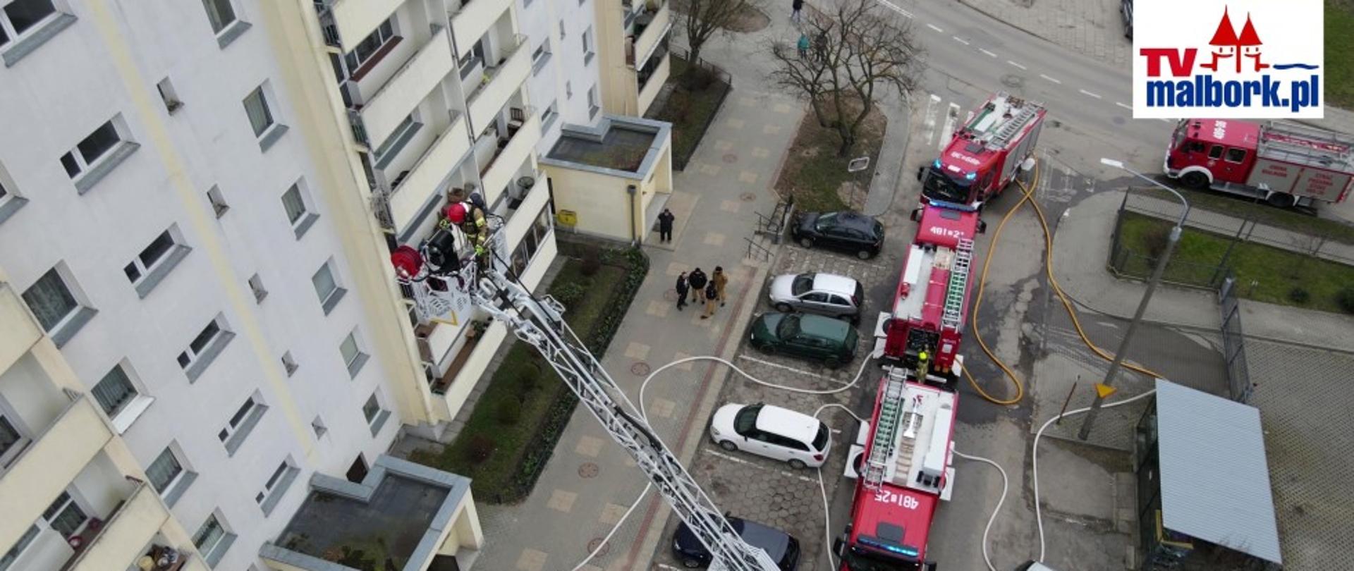 Strażak w koszu drabiny mechanicznej wjeżdża na 10 piętro budynku mieszkalnego