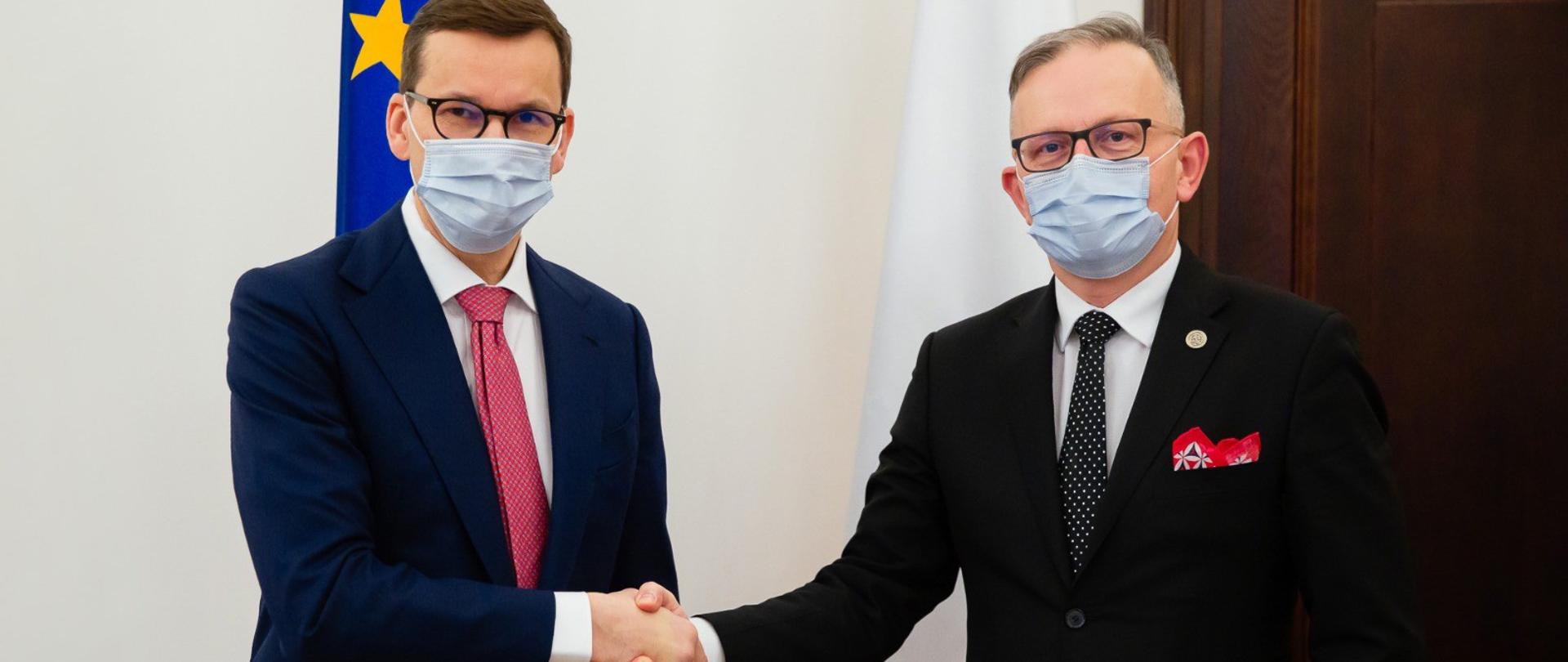 Uścisk dłoni, premier Mateusz Morawiecki i z-ca szefa KAS Mariusz Gojny.