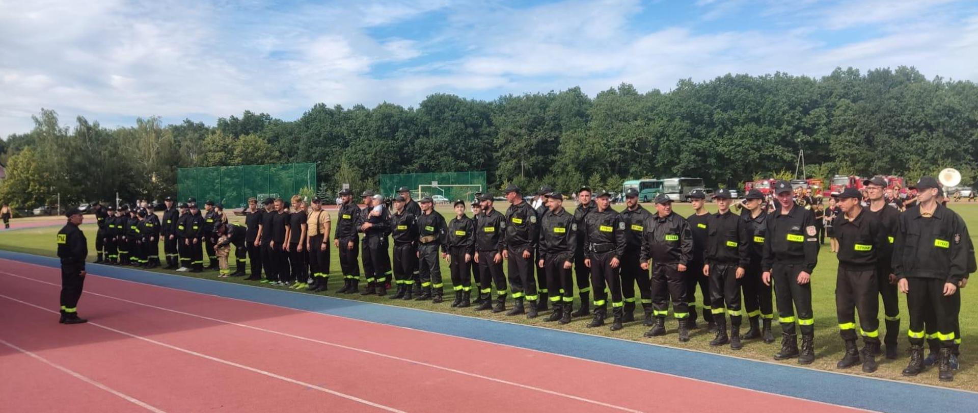 Gminne Zawody Sportowo-Pożarnicze w Osięcinach. Zdjęcie przedstawia strażaków OSP Gminy Osięciny ubranych w ubrania koloru czarnego, biorących udział w zawodach. 