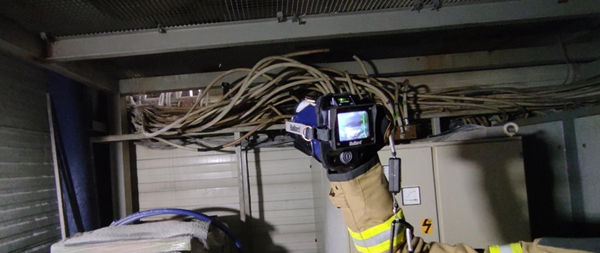 Strażak dokonujący kontroli temperatury miejsca pożaru za pomocą kamery termowizyjnej