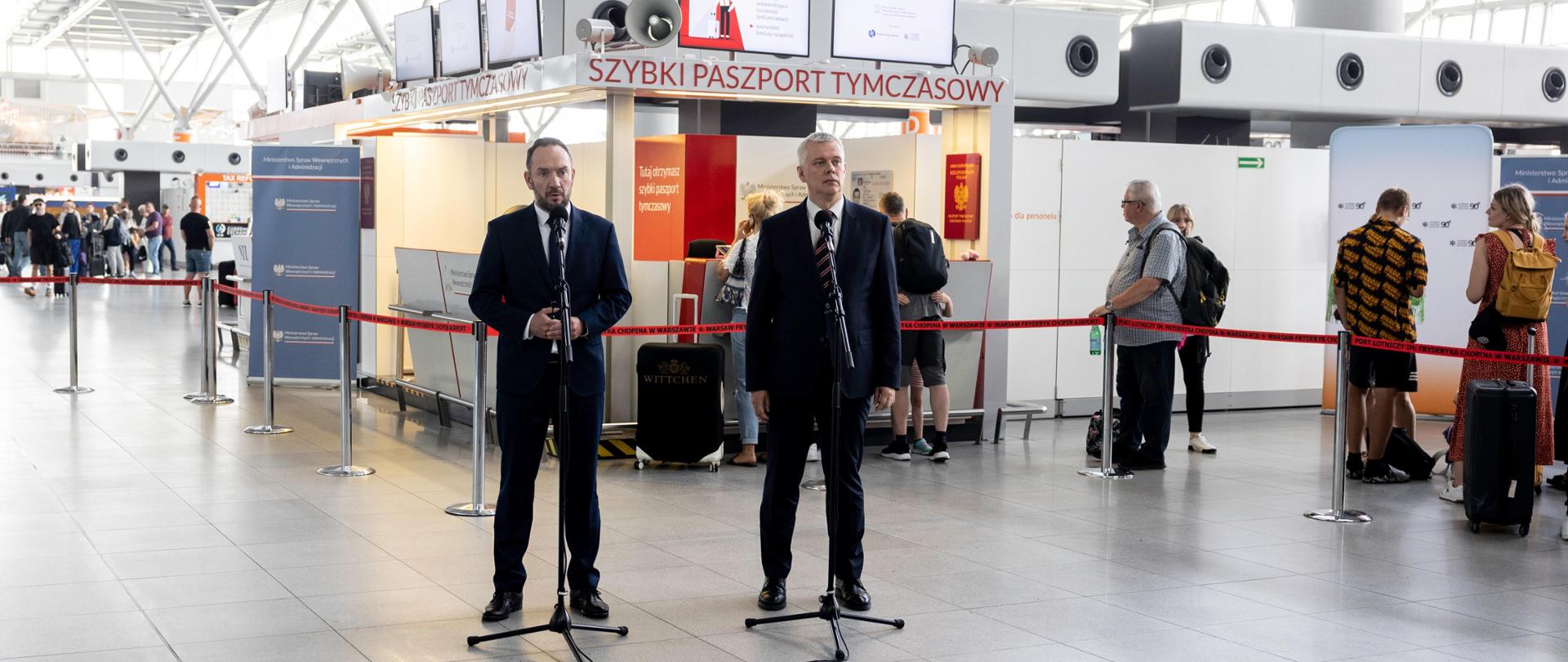 Na zdjęciu widać dwóch mężczyzn, stojących przy mikrofonach
