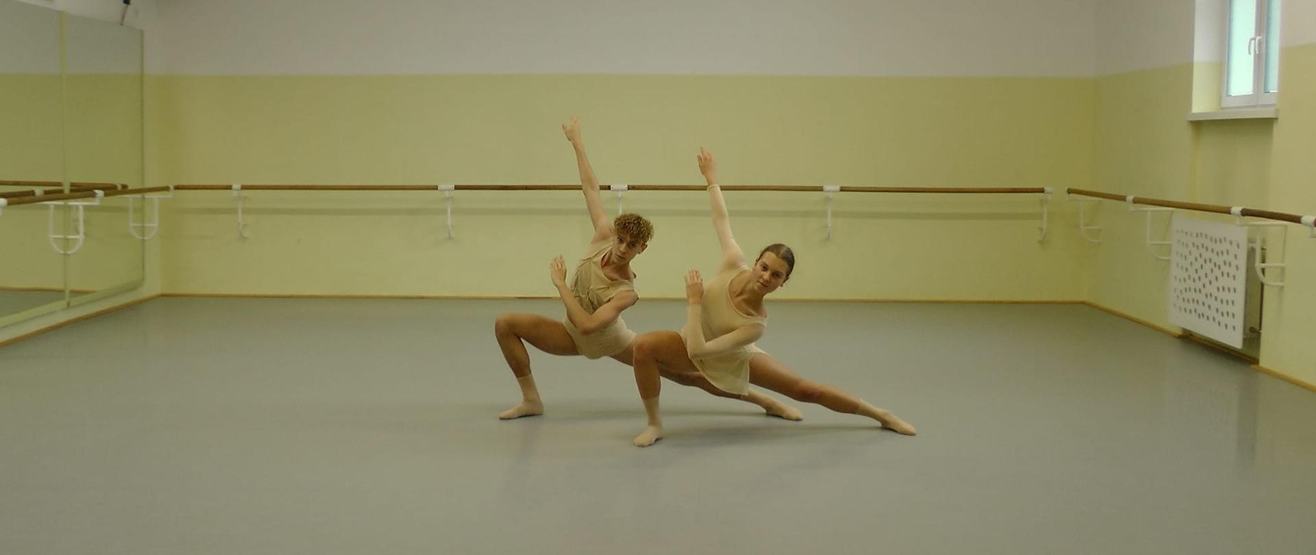 zdjęcie: para uczniów szkoły baletowej ubranych w cieliste stroje tańczących na sali baletowej