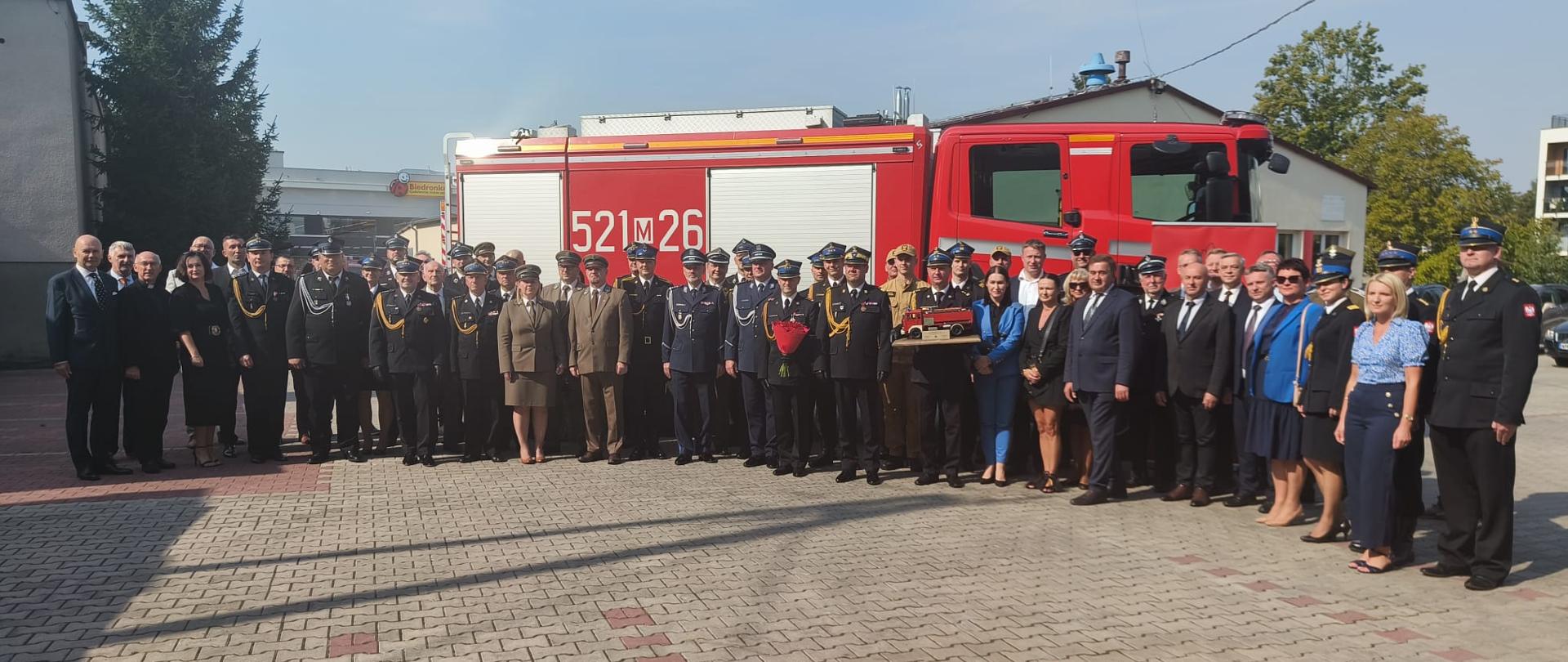 zdjęcie grupowe uczestników uroczystości na tle samochodu gaśniczego 