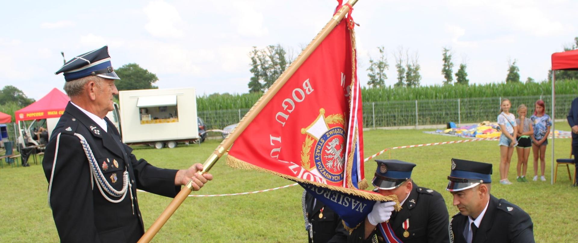 Na zdjęciu widocznych jest czterech mężczyzn ze sztandarem