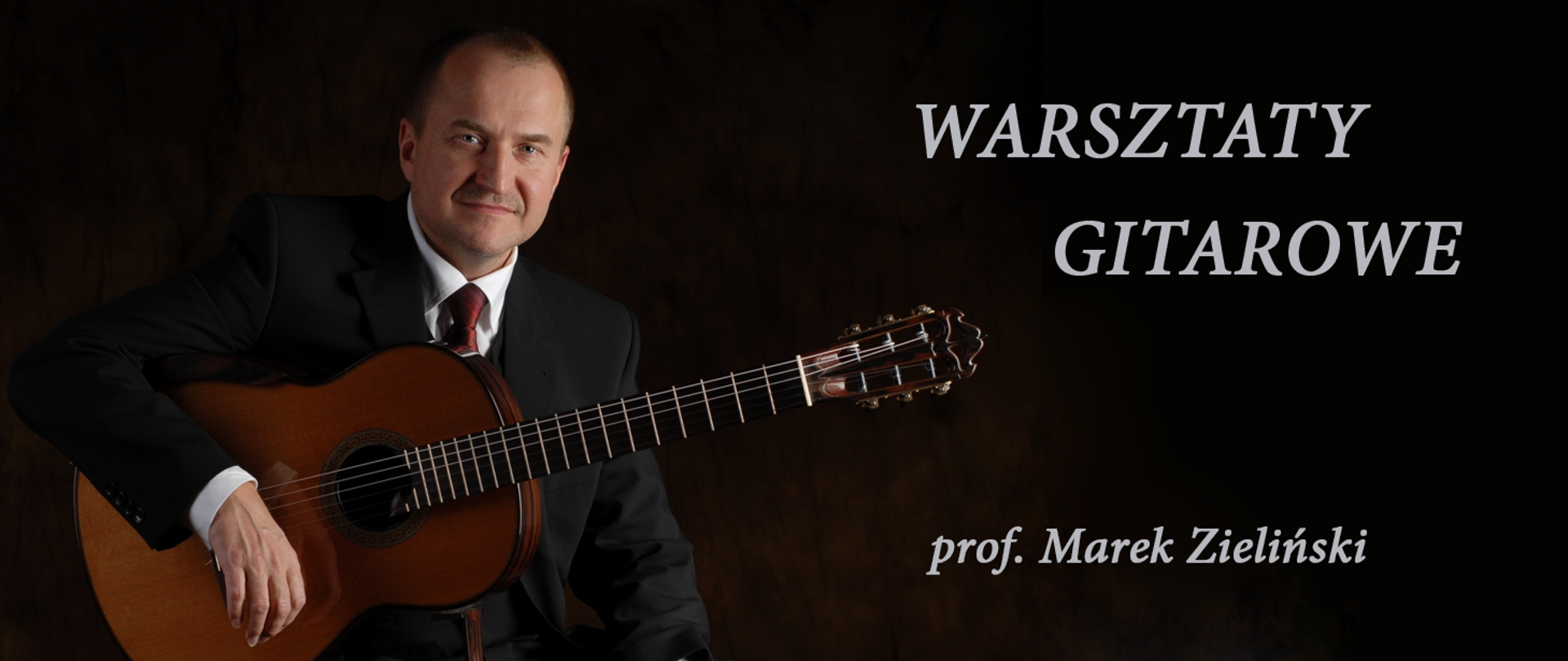 Baner przedstawia zdjęcie profesora oświaty Marka Zielińskiego trzymającego gitarę. Tło zdjęcia jest ciemne, z prawej strony umieszczono napis „WARZSTATY GITAROWE prof. Marek Zeliński”.