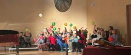 Na sali koncertowej szkoły odbywa się koncert pt. karnawał lalek. Dzieci są ubrane w kolorowe stroje a sala przyozdobiona kolorowymi balonami.
