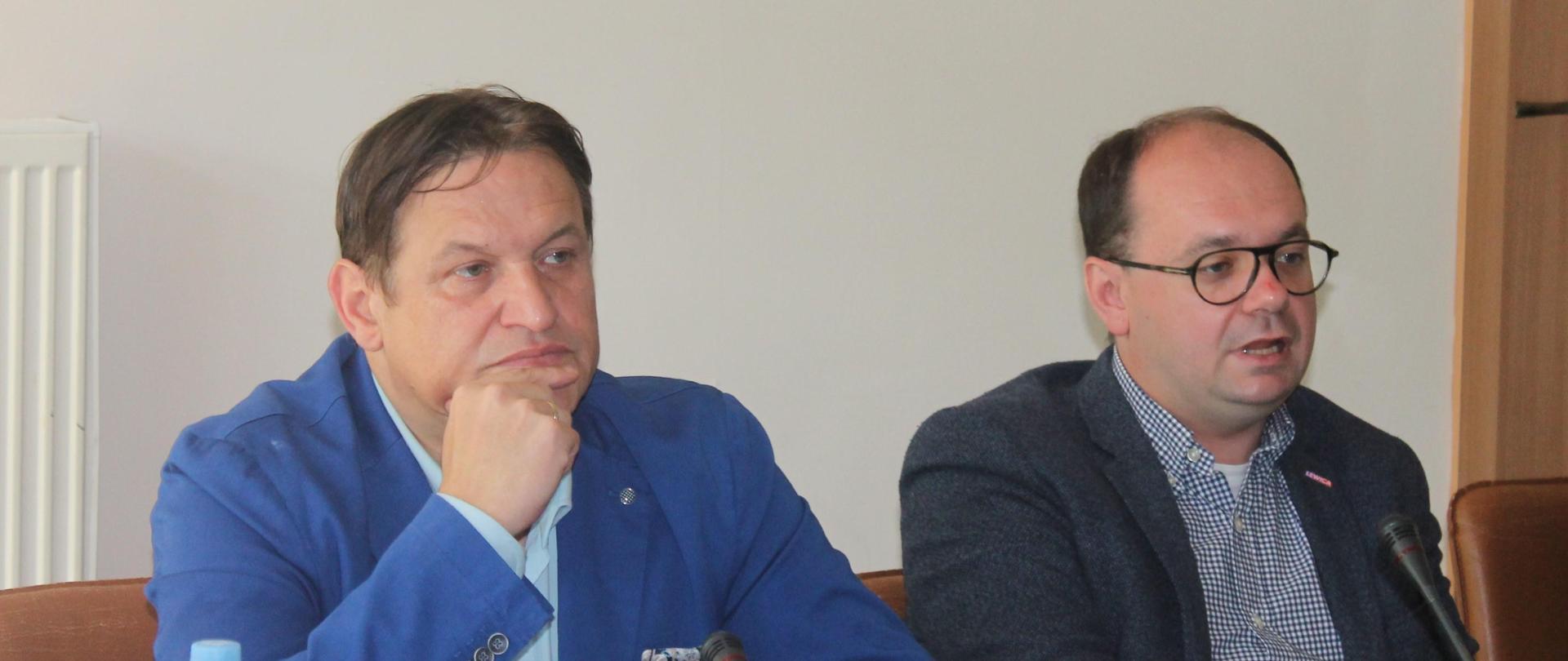 Zdjęcie przedstawia stół prezydialny, za którym siedzą Pan Jacek Męcina, Przewodniczący Zespołu oraz Pan Sebastian Gajewski, Podsekretarz Stanu w Ministerstwie Rodziny, Pracy i Polityki Społecznej