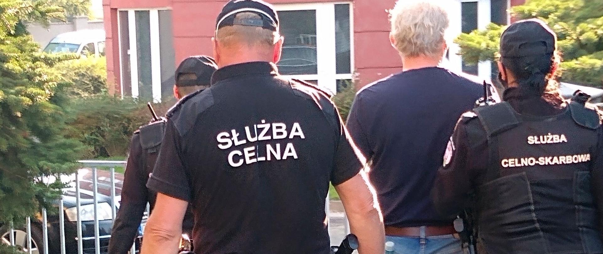 Funkcjonariusze Służby Celno-Skarbowej prowadzą zatrzymanego.