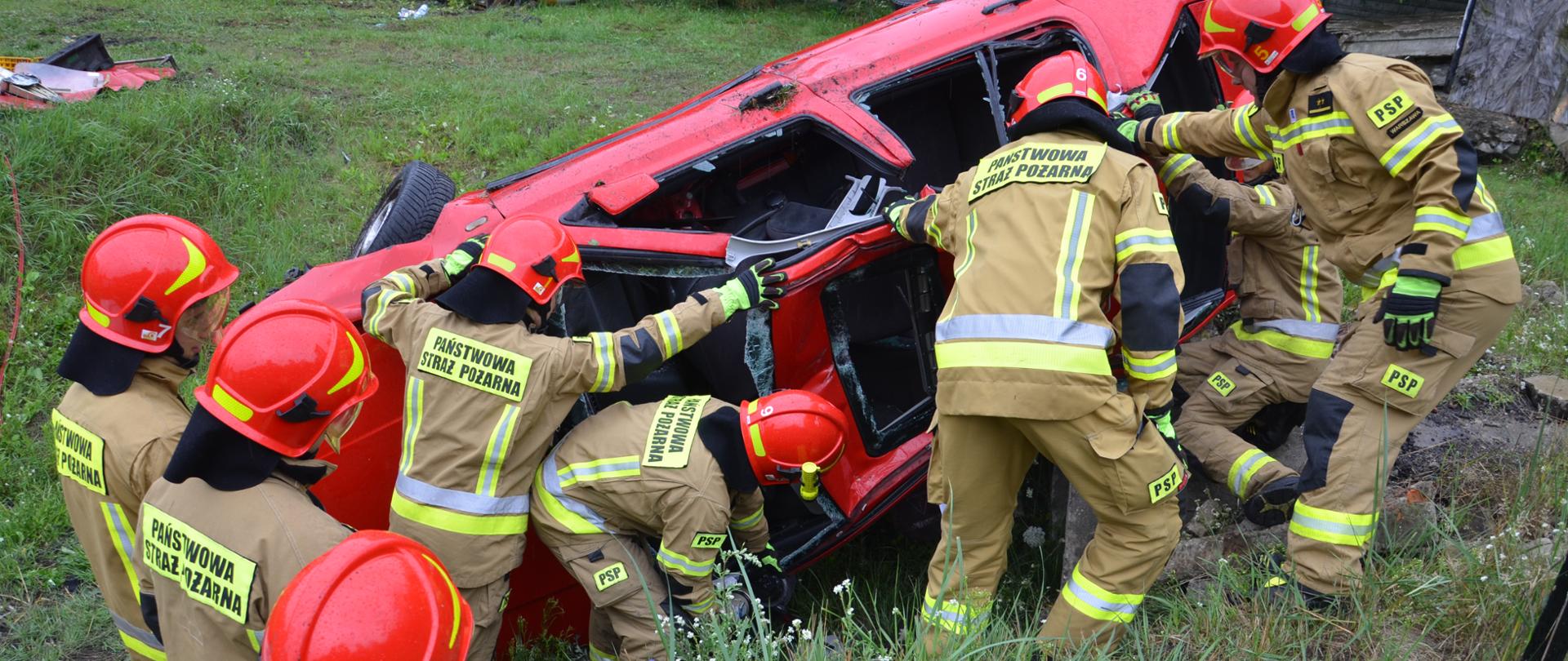 strażacy podczas zajęć praktycznych na poligonie szkoleniowym w ośrodku szkolenia w pionkach wykonują stabilizację pojazdu oraz wycinanie elementów karoserii samochodu