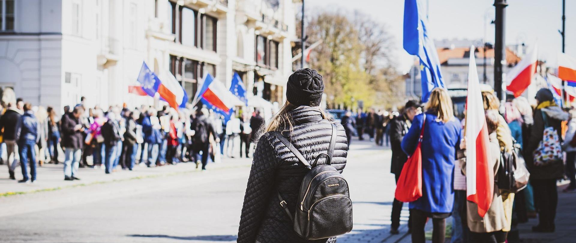 Demonstranci na ulicy powiewają flagami Polski i Unii Europejskiej