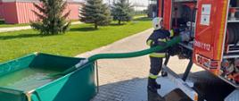 Strażak - ratownik z jednostki Ochotniczej Straży Pożarnej podczas obsługi autopompy samochodu pożarniczego