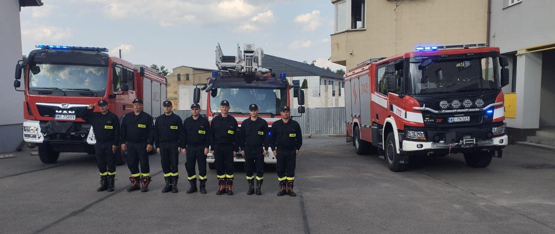 Strażacy oddają hołd przed pojazdami pożarniczymi