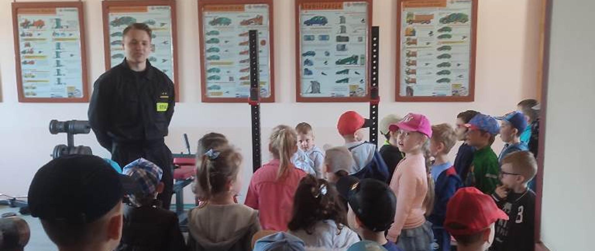 Sala ćwiczeń w JRG, dzieci oglądają wyposażenie siłowni oraz plakaty z materiałami dydaktycznymi rozwieszonymi na ścianach 