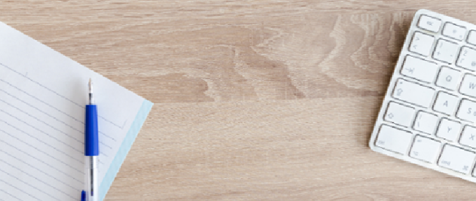 Zdjęcie przedstawia klawiaturę oraz kartkę z papierem położone na biurku