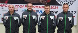 Reprezentacja Strażaków Państwowej Straży Pożarnej województwa opolskiego w Tenisie Stołowym. Strażacy w strojach sportowych stoją na tle banneru mistrzostw. 40. Mistrzostwa Polski Strażaków Państwowej Straży Pożarnej w Tenisie Stołowym. Reprezentacja strażaków woj. opolskiego w skladzie: mł. bryg. Piotr Gerlic - KM PSP Opole, st. kpt. Mateusz Nieświec - KP PSP Strzelce Opolskie, asp. sztab. Tomasz Wdowik - KP PSP Strzelce Opolskie, st. asp. Grzegorz Duda - KP PSP Strzelce Opolskie zajęła wysokie 4 miejsce.