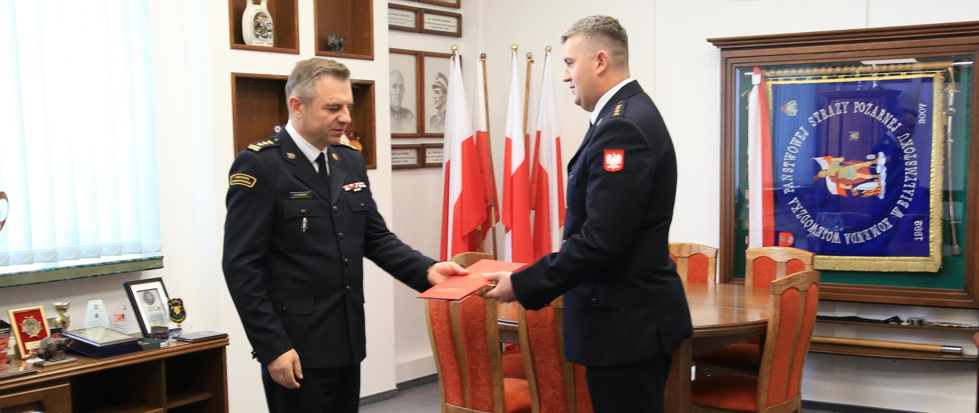 Podlaski Komendant Wojewódzki PSP gratuluje przez uścisk dłoni nowo powołanemu zastępcy komendanta miejskiego PSP w Łomży. Obaj strażacy ubrani w mundury wyjściowe