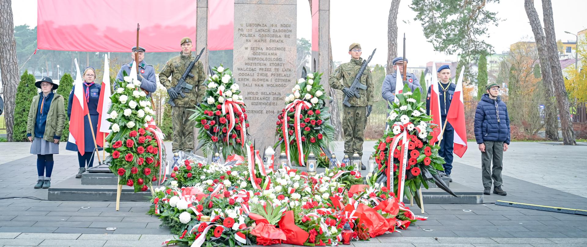 pomnik Niepodległej w Kozienicach, przed nim wiązanki kwiatów i warty honorowe