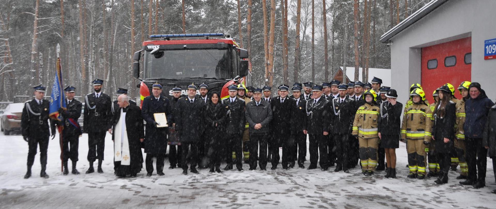 Na zdjęciu na tle pojazdu pożarniczego zaproszeni goście oraz druhowie OSP. Uroczystość odbywa się z okazji przekazania pojazdu gaśniczego dla OSP Otwock Jabłonna