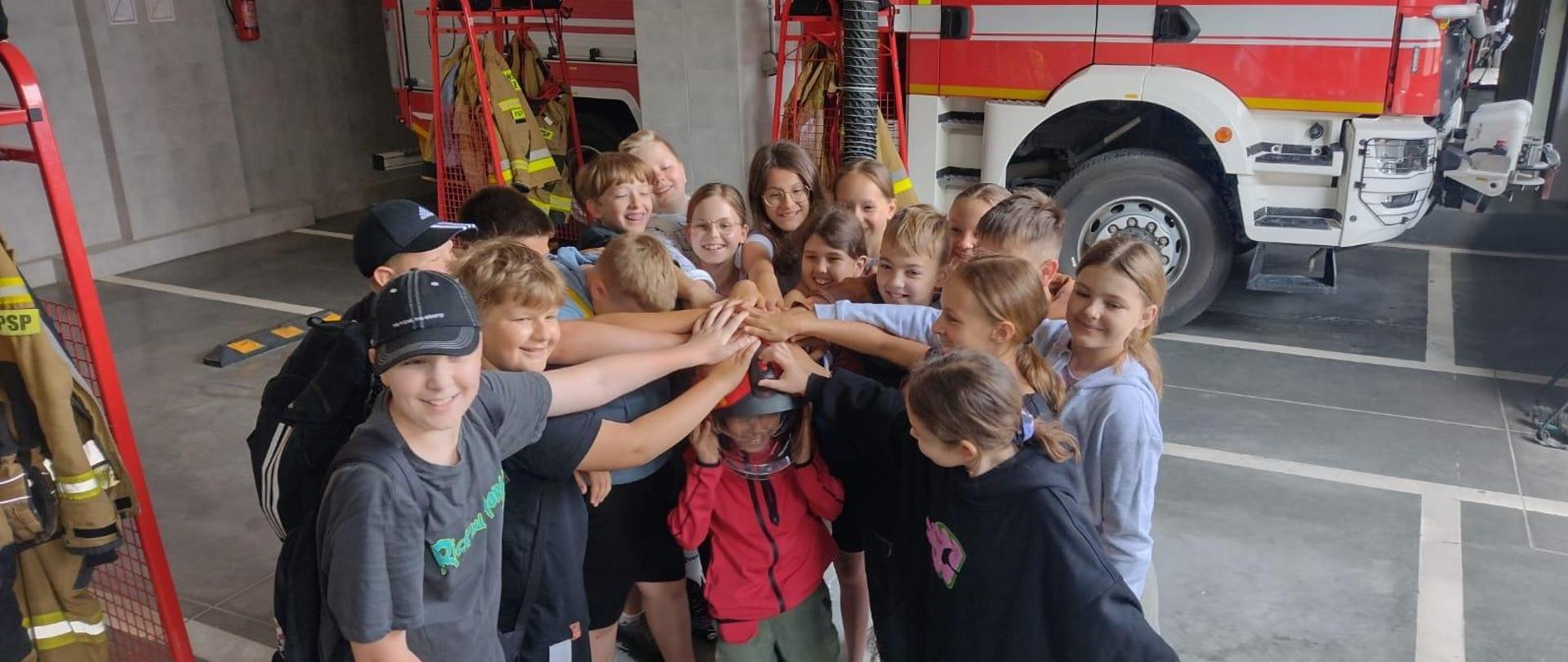 Grupa dzieci w garażu bojowym strażaków.