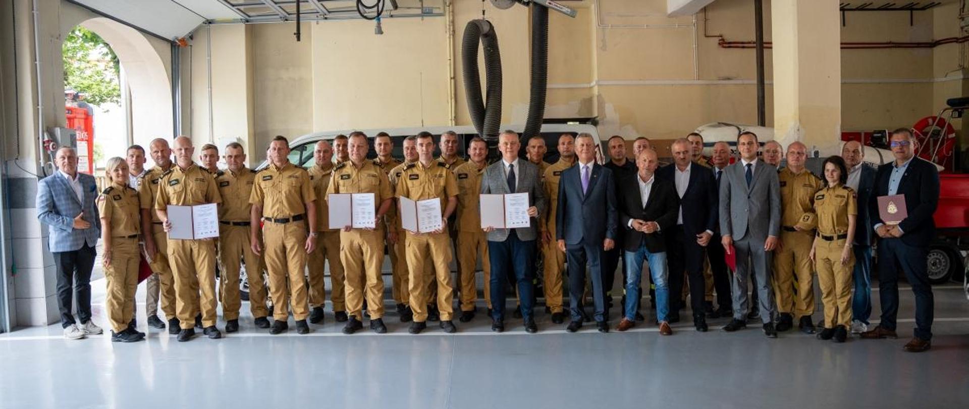 Wspólne zdjęcie sygnatariuszy, zaproszonych gości i strażaków. Zdjęcie wykonane na garażu Jednostki Ratowniczo-Gaśniczej w Nysie.