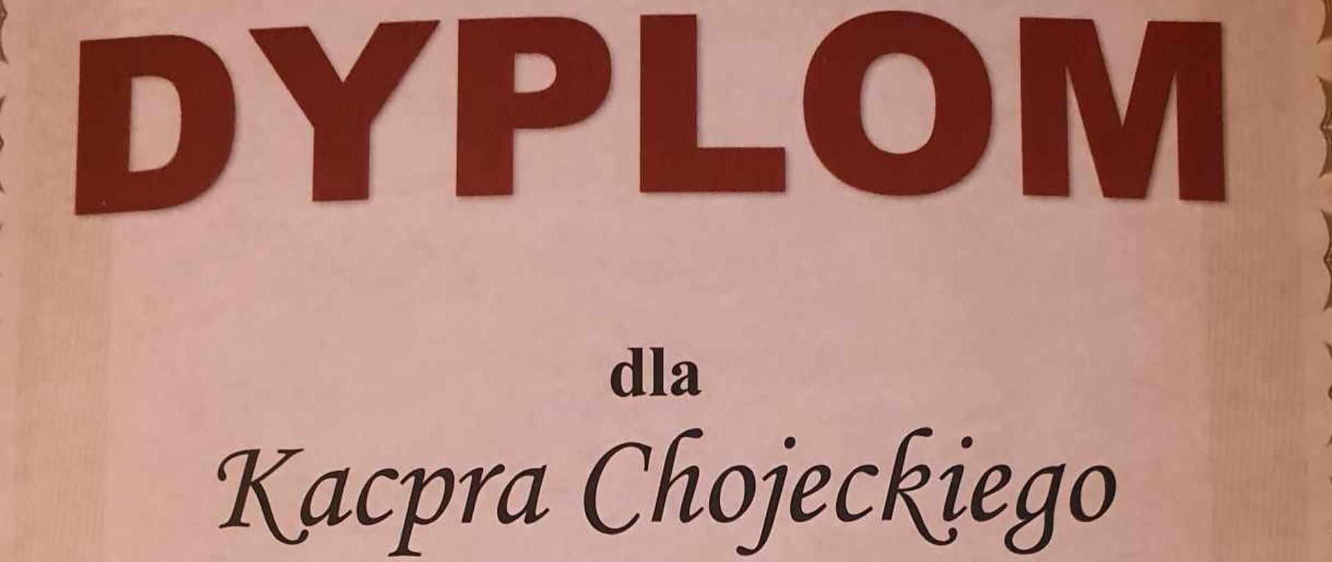 Zdjęcie dyplomu. Na beżowym tle napis dyplom dla Kacpra Chojeckiego ucznia PSM I st. w Pułtusku z klasy pana Jacka Siemiątkowskiego za zajęcie I miejsca w grupie pierwszej w 6 Ogólnopolskim Konkursie Młodych Gitarzystów im. Kazimierza Sosińskiego. Na dyplomie podpisy przewodniczącego i członków jury oraz pieczęć PSM I st. w Łodzi.