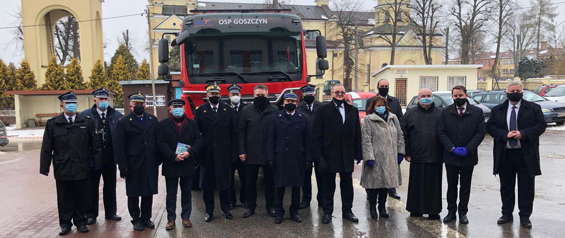 Zdjęcie przedstawia 15 osób, które stoją na tle nowego samochodu gaśniczego OSP Goszczyn