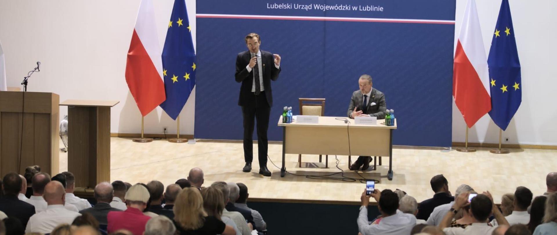 Na scenie wiceminister Jan Szyszko z mikrofonem. Przed nim publiczność.
