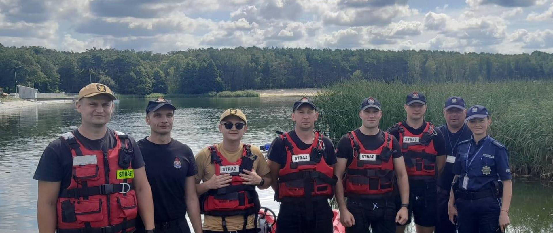 Zdjęcie grupowe uczestników patrolu wodnego, strażaków i policjantów, w tle widoczne jezioro